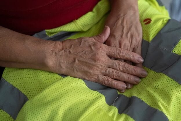Manos de persona mayor sobre pantalón reflectante