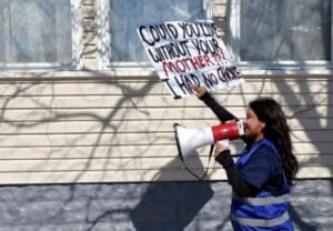 Mujer protesta con megáfono y pancarta reivindicativa